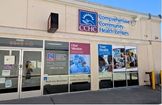 Front entrance of a Comprehensive Community Health Centers building with posters about health services and a blue CCHC logo above the door.